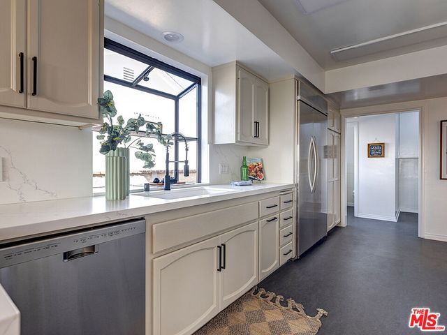 a kitchen with white cabinets and a window