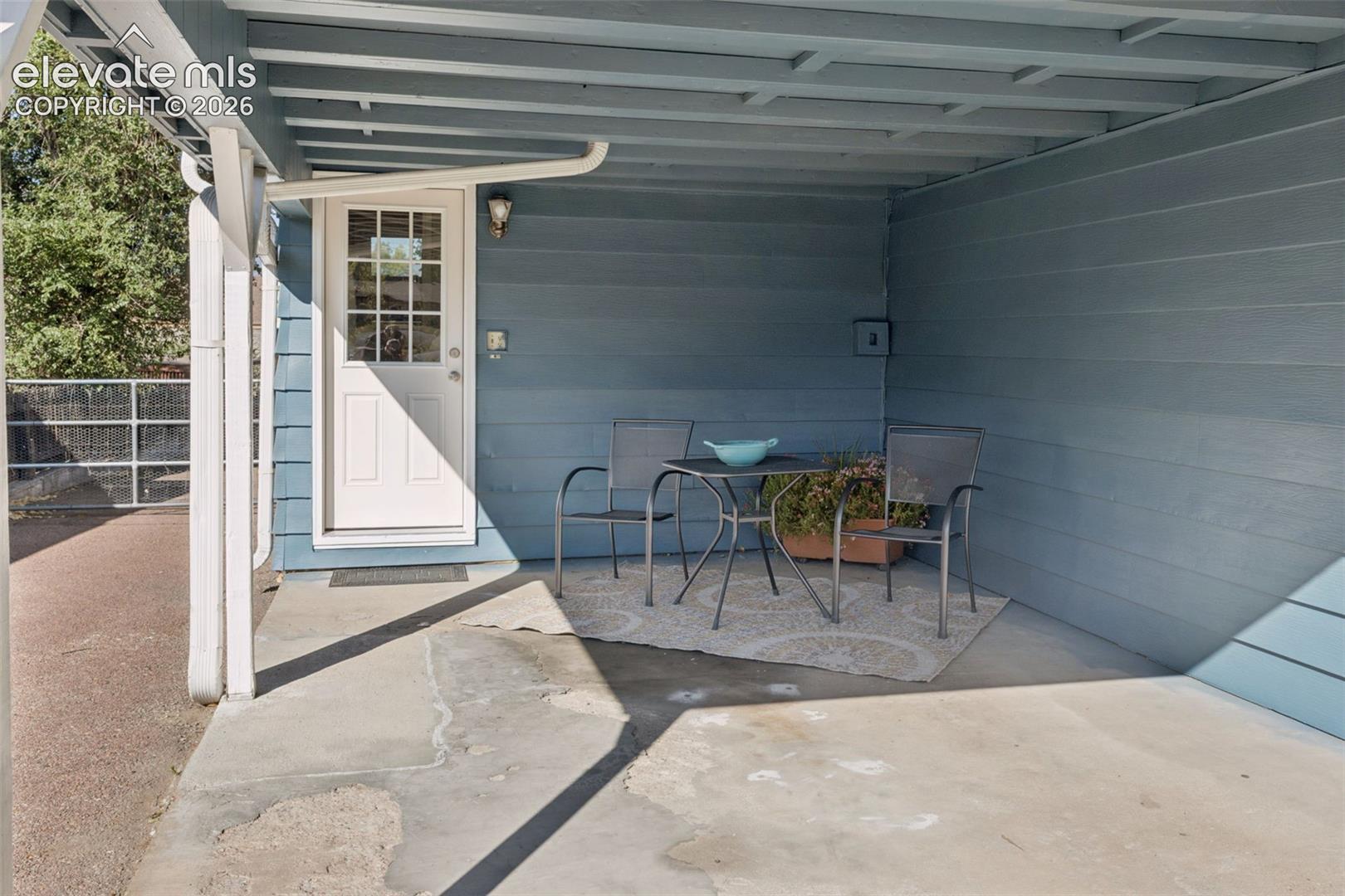 4004 Mallow Road Colorado Springs, CO 80907 - Photo 43 of 50 Covered concrete patio with painted siding, a white paneled door with glass inserts, and an overhead lighting fixture