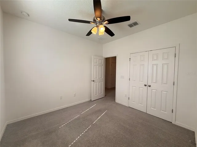 an empty room with ceiling fan and windows