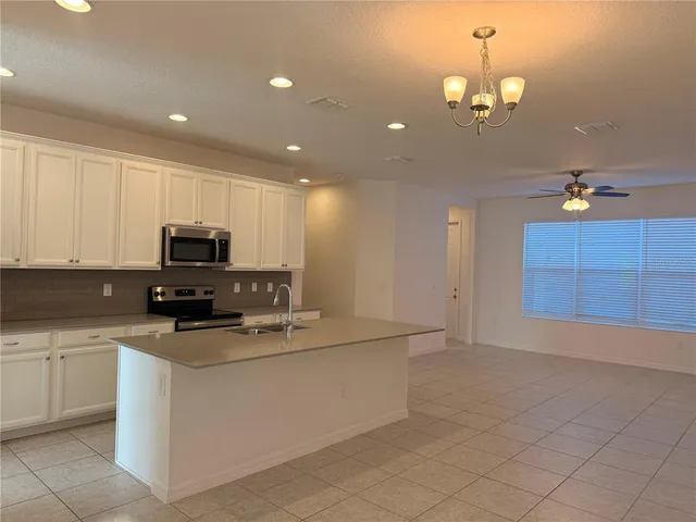 a kitchen with kitchen island granite countertop a sink a counter top space appliances and cabinets