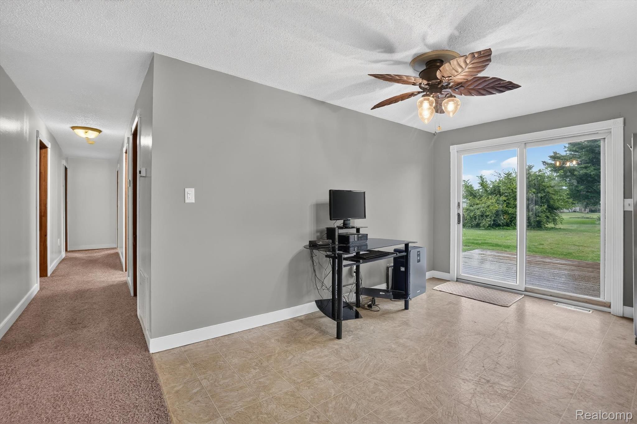 10977 Maple Road Birch Run, MI 48415 - Photo 10 of 49 Sliding glass door, leaf-design ceiling fan with integrated lighting, neutral wall paint, tiled flooring, and a carpeted hallway