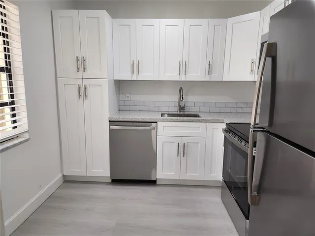 a kitchen with white cabinets and stainless steel appliances