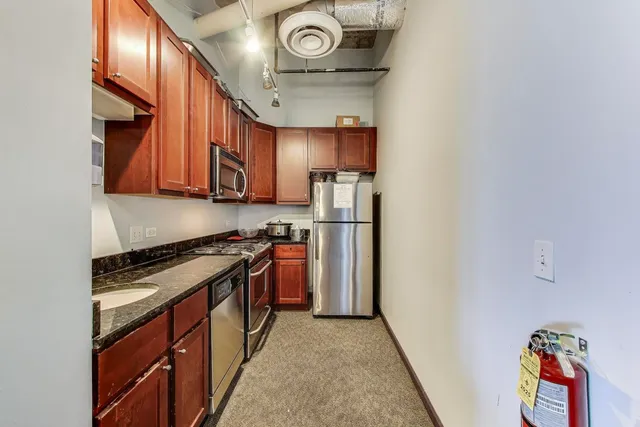 a kitchen with stainless steel appliances granite countertop a stove and a refrigerator with cabinets