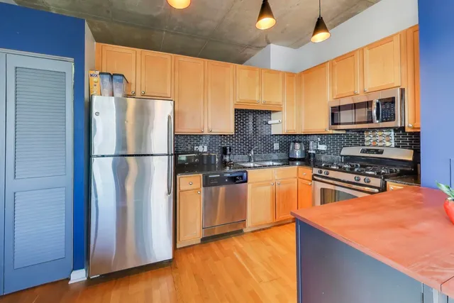 a kitchen with stainless steel appliances granite countertop a refrigerator a stove top oven a sink and dishwasher