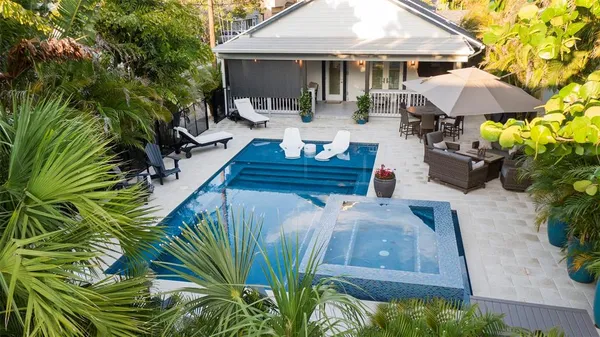 a view of a patio with table and chairs under an umbrella with potted plants