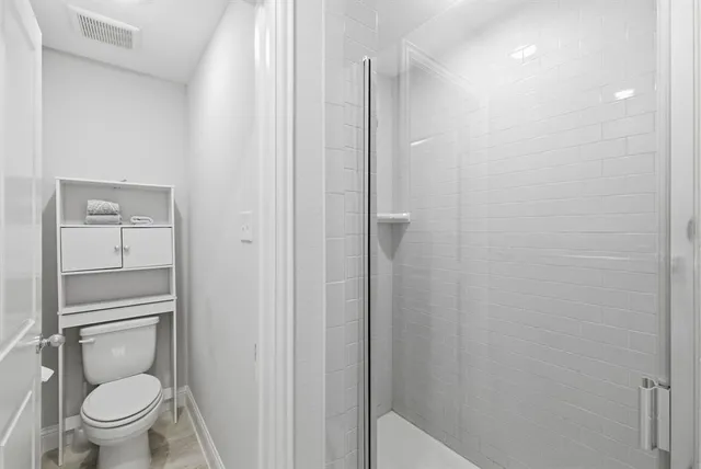 a white toilet sitting next to a shower