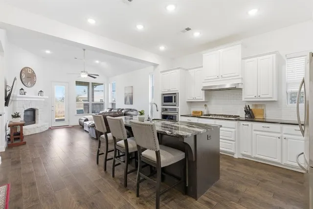 a open kitchen with granite countertop lots of white cabinets appliances and furniture