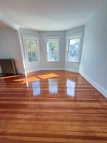 a view of empty room with window and wooden floor