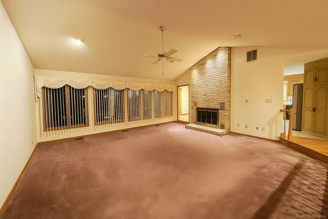 an empty room with floor to ceiling windows and fireplace