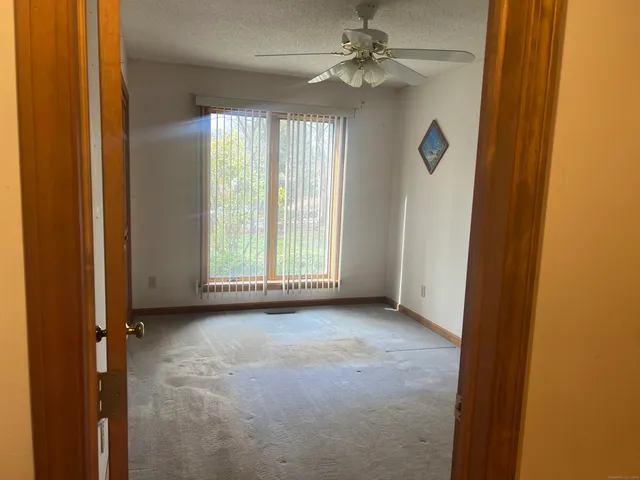 an empty room with windows and fan