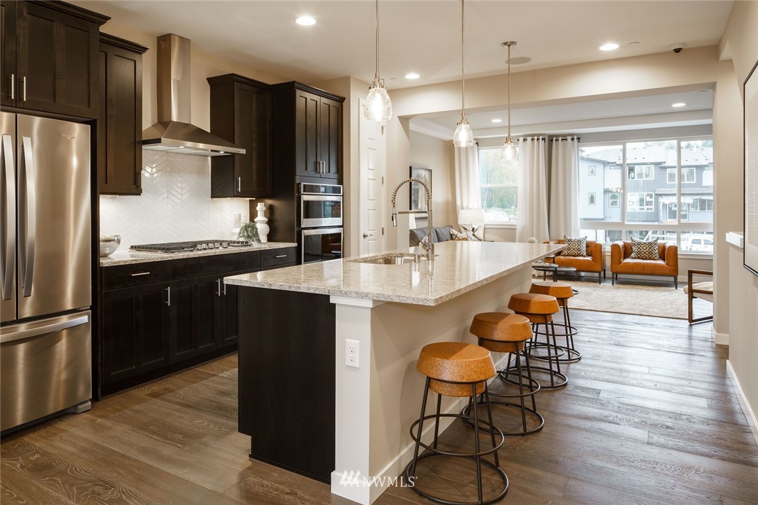 619 238th Street Southeast, Unit B Bothell, WA 98021 - Photo 7 of 20 a kitchen with granite countertop a refrigerator a sink a stove and chairs with wooden floor