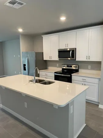 a kitchen with kitchen island a sink a stove a refrigerator and white cabinets