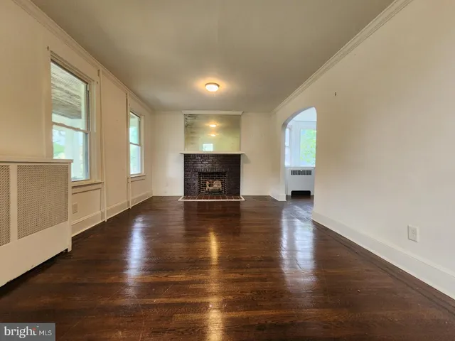 an empty room with wooden floor and a fireplace