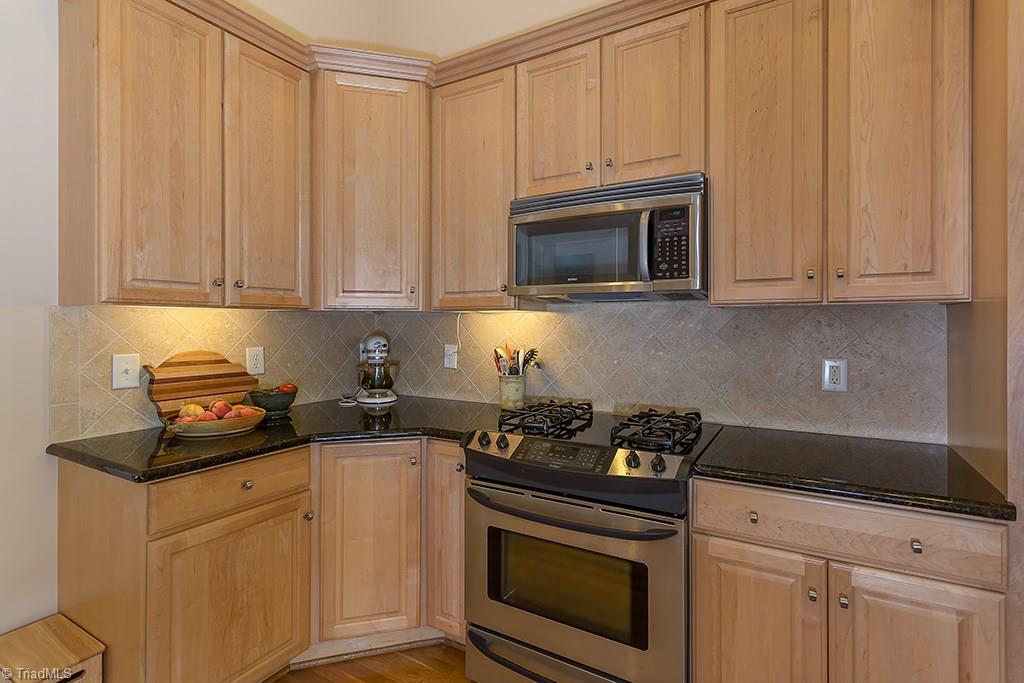 5803 Beckenham Way Oak Ridge, NC 27310 - Photo 7 of 28 Neutral dcor with tile backsplash. Plenty of cabinets with corner lazy susans.