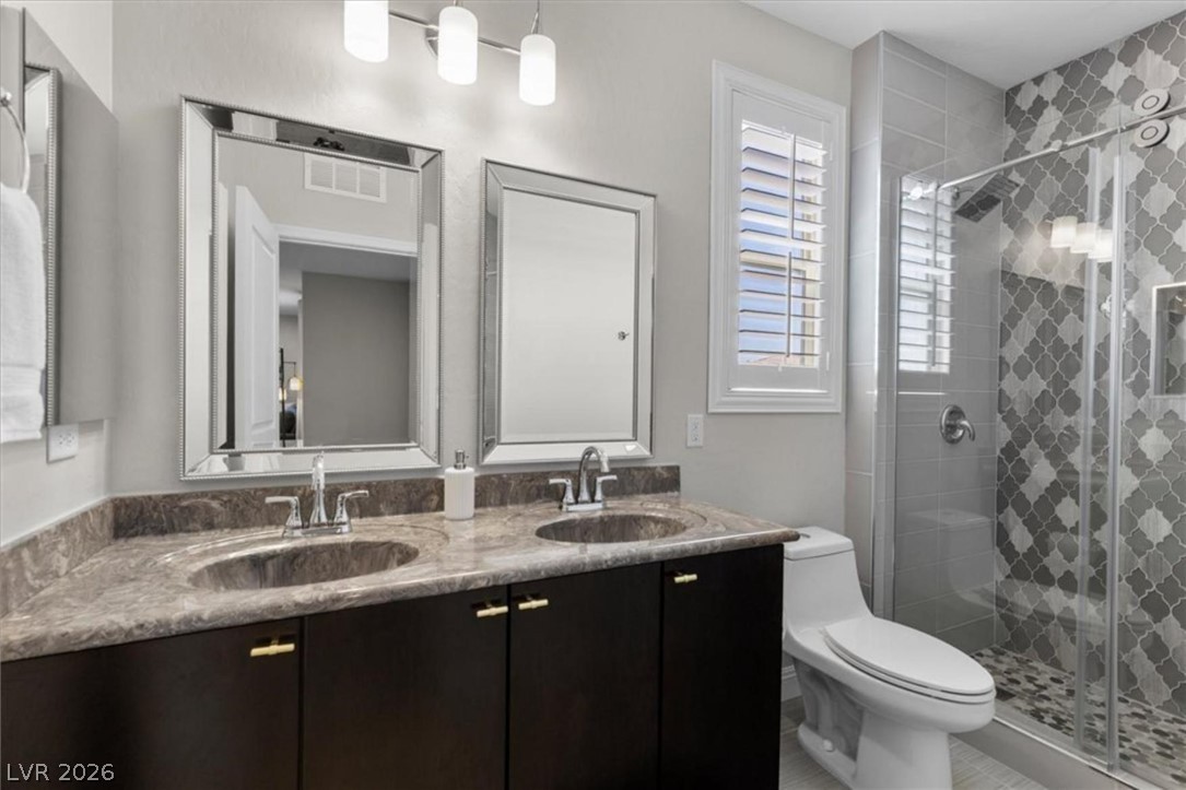 10334 Mopan Road Las Vegas, NV 89178 - Photo 21 of 28 The hall bath serves the secondary bedrooms with a dual vanity and glass enclosed shower.