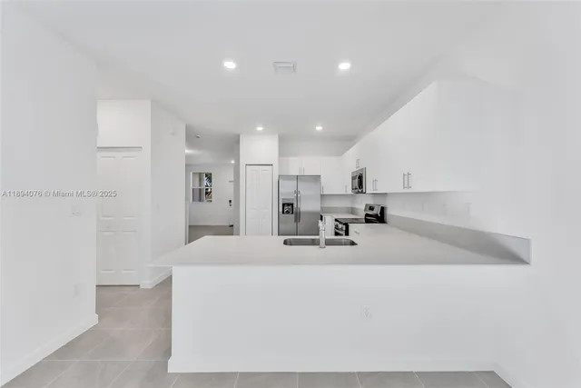 a large white kitchen with kitchen island a sink a stove and a refrigerator
