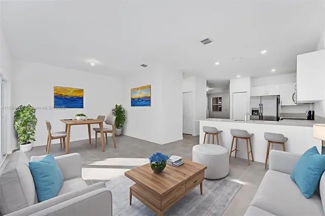 a living room with furniture kitchen view and a potted plant