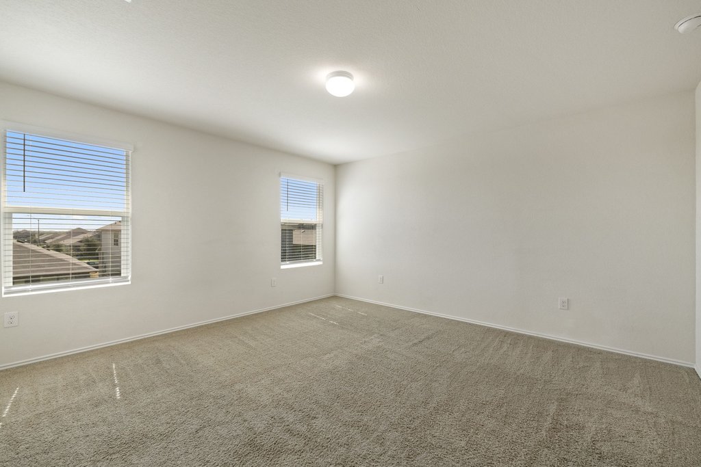 15011 Tuff Rd Manor Manor, TX 78653 - Photo 23 of 37 Primary bedroom with soft carpet, neutral paint, and two large windows overlooking the neighborhood.