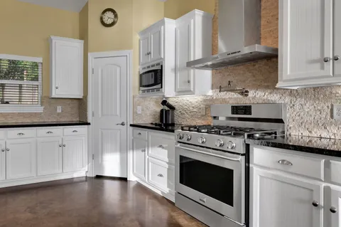 a kitchen with stainless steel appliances granite countertop a stove a sink and a microwave