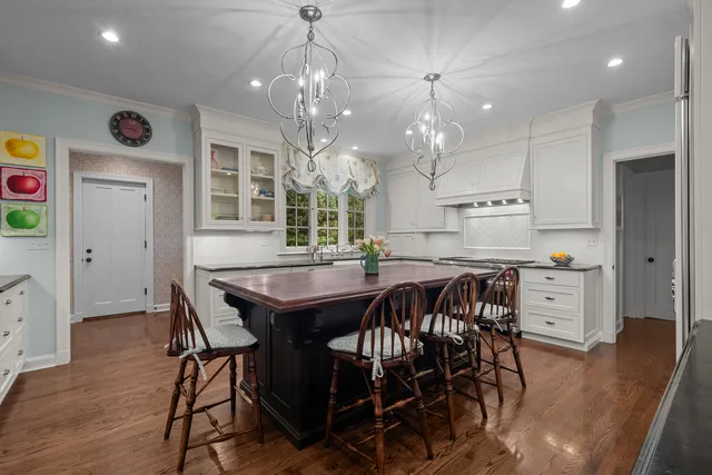 a kitchen with stainless steel appliances granite countertop a table chairs and a wooden floors