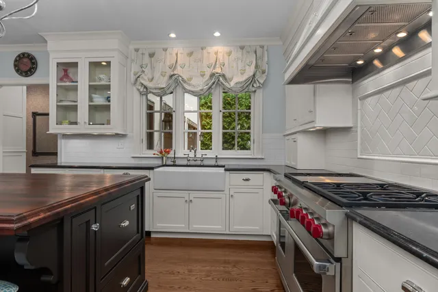 a kitchen with stainless steel appliances granite countertop a sink a stove and a wooden floors