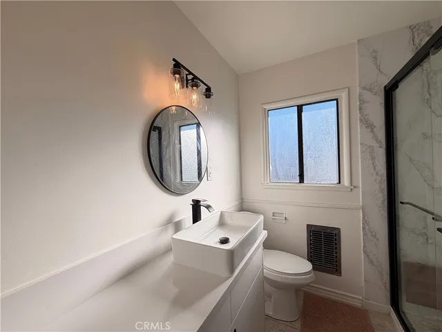 a bathroom with a granite countertop shower and mirror
