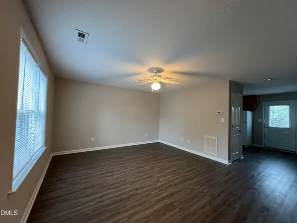 a view of an empty room with wooden floor and a ceiling fan