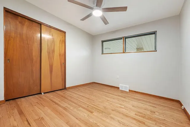 an empty room with wooden floor closet and windows