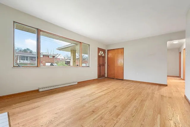 a view of an empty room with wooden floor and a window