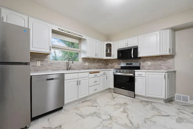 a kitchen with granite countertop white cabinets and appliances