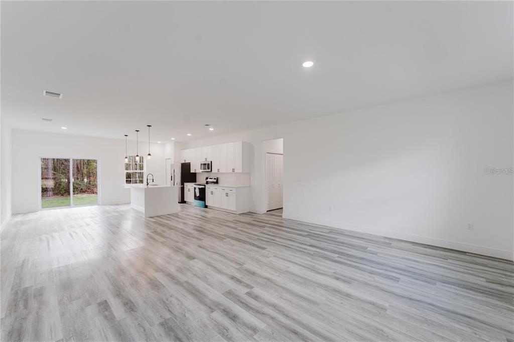 6732 Southwest 132nd Street Ocala, FL 34473 - Photo 6 of 36 a view of a livingroom with wooden floor and kitchen view