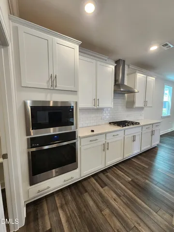 a large white kitchen with kitchen island a sink a stove and wooden floor