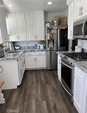a kitchen with stainless steel appliances granite countertop a stove a sink and a refrigerator