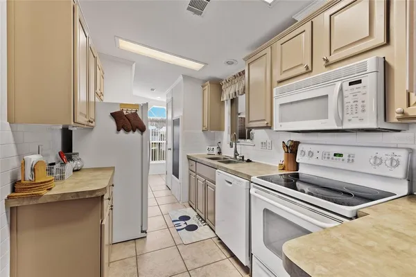 a kitchen with stainless steel appliances granite countertop a stove a sink a refrigerator and white cabinets