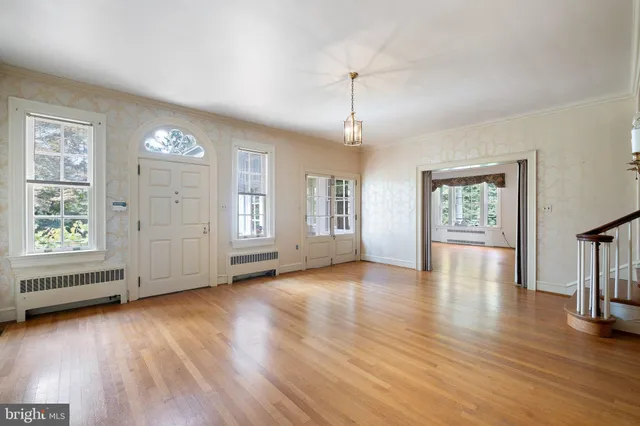 an empty room with wooden floor chandelier and windows
