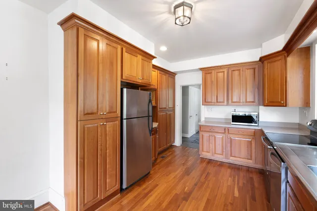 a kitchen with a refrigerator a sink dishwasher and a stove with wooden floor