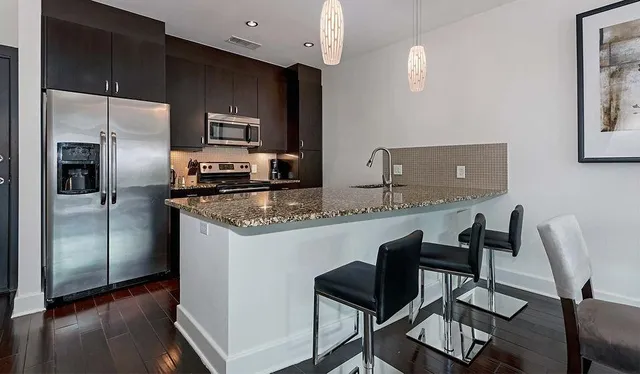 a kitchen with stainless steel appliances granite countertop a sink refrigerator stove and microwave