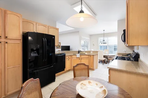 a kitchen with stainless steel appliances granite countertop a refrigerator a stove a sink dishwasher and a dining table with wooden floor