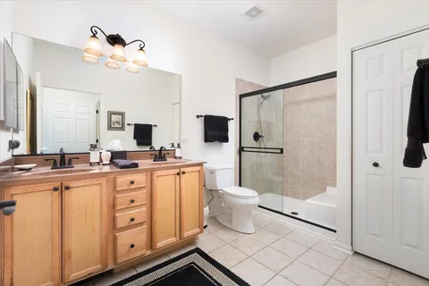 a bathroom with a double vanity sink a toilet a mirror and shower