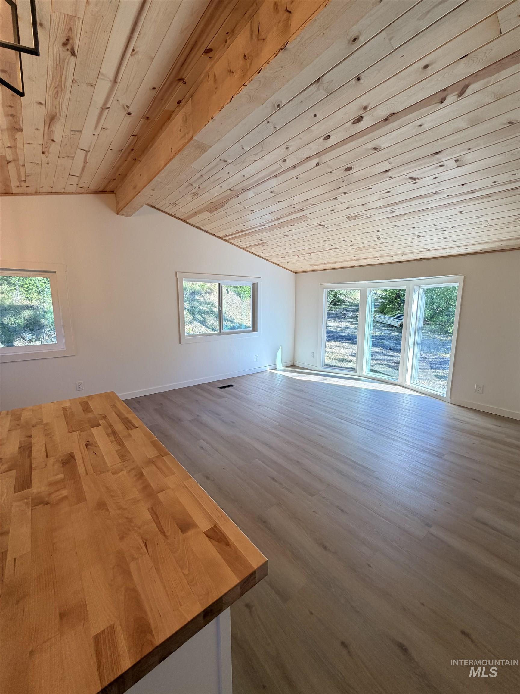 151 View Road Kamiah, ID 83536 - Photo 15 of 49 Open-concept living area featuring a vaulted wood-plank ceiling with exposed beams, light wood-finish flooring, and bright white walls