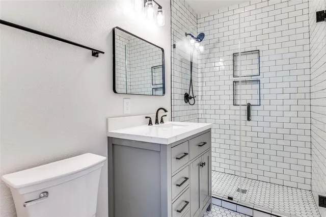 a bathroom with a granite countertop sink a toilet and a mirror
