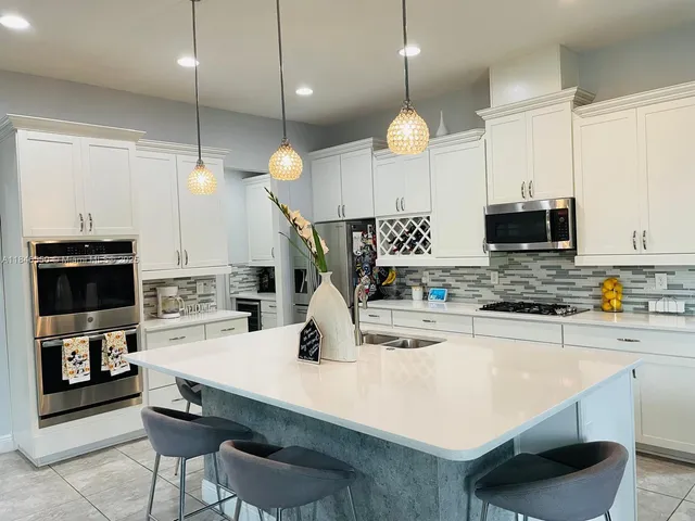 a kitchen with a sink a microwave a stove and chairs