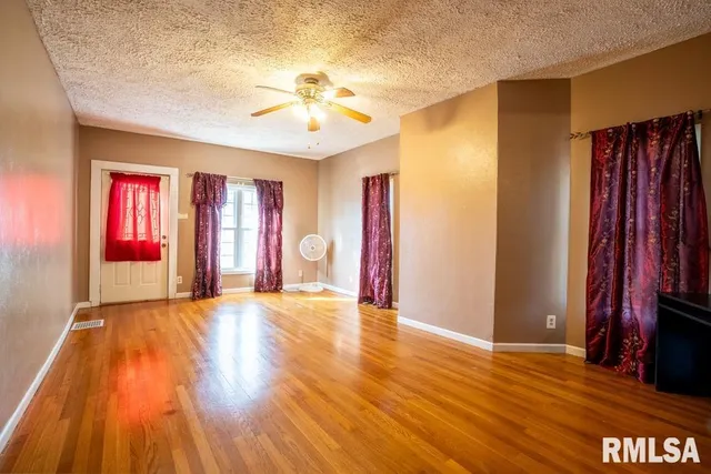 a view of an empty room with window and wooden floor