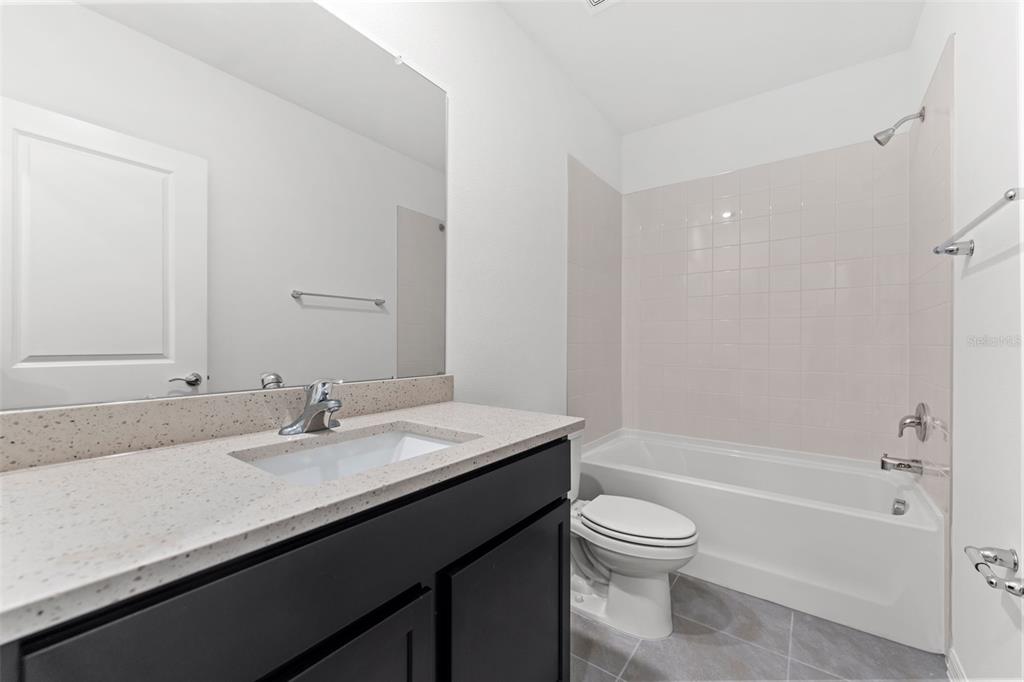 31336 Paper Birch Street Wesley Chapel, FL 33545 - Photo 24 of 38 a bathroom with a granite countertop sink a toilet and bathtub