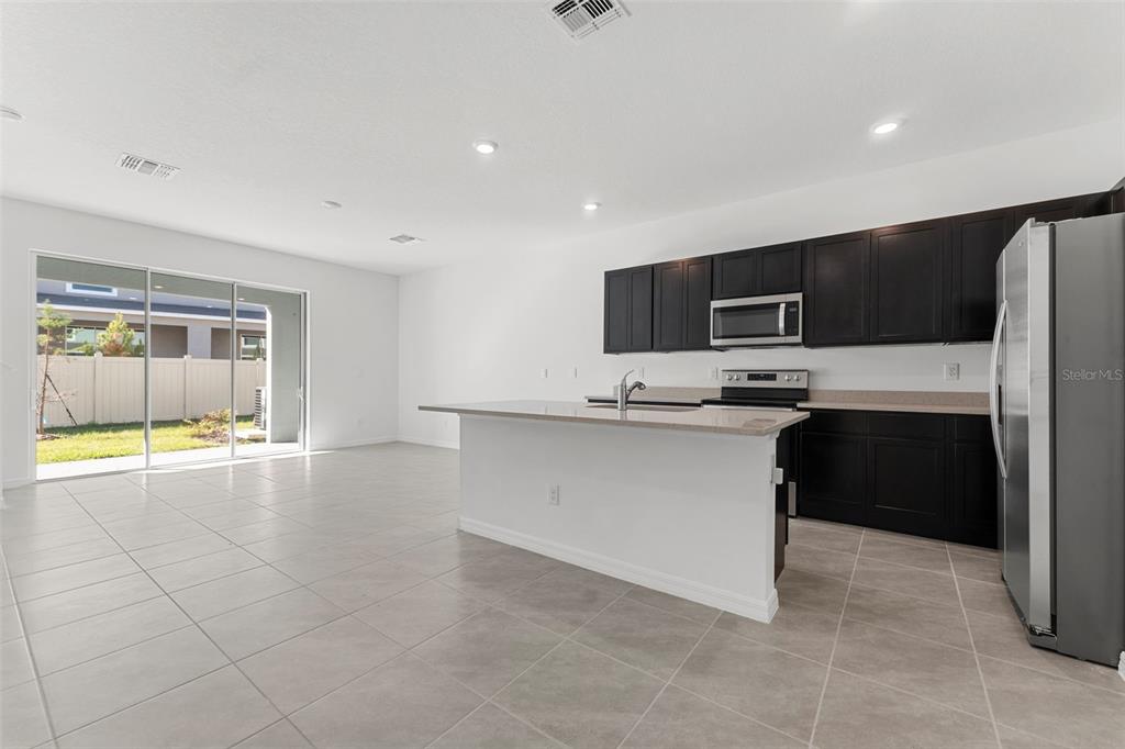 31336 Paper Birch Street Wesley Chapel, FL 33545 - Photo 9 of 38 a kitchen with a refrigerator and a stove top oven