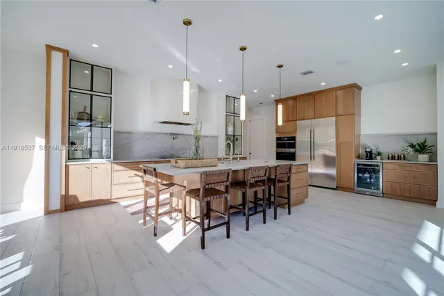 a kitchen with stainless steel appliances granite countertop a kitchen island a stove a sink a dining table and chairs with wooden floor