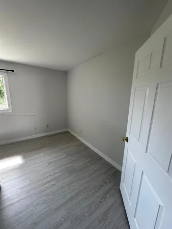 an empty room with wooden floor and window