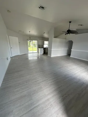 a view of empty room with wooden floor and window