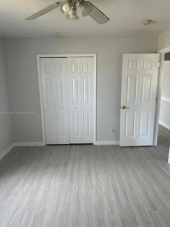 an empty room with wooden floor chandelier fan and windows