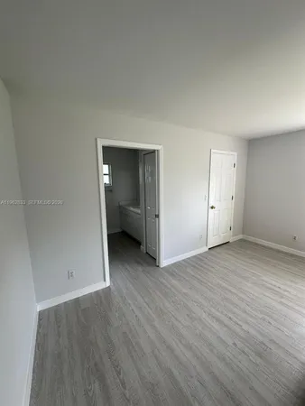 an empty room with wooden floor & bathroom view